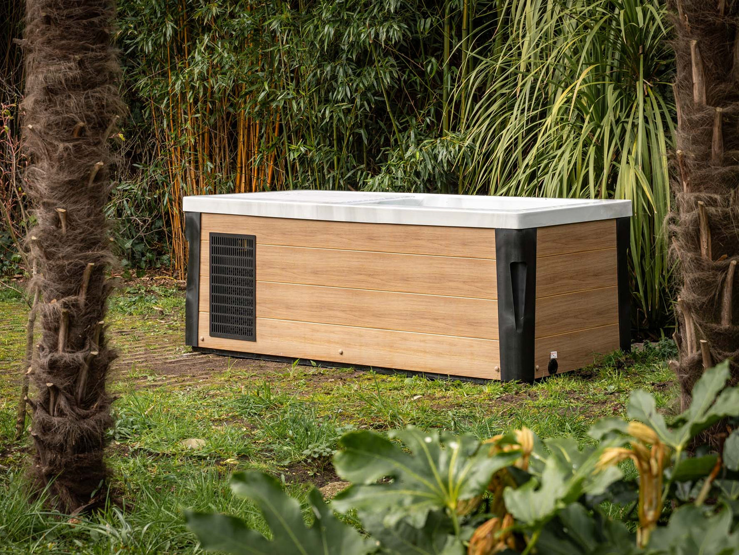 Breeze Ice Bath with Current in outdoor garden setting, bamboo-toned exterior, surrounded by tropical plants - Passion Ice Baths Collection