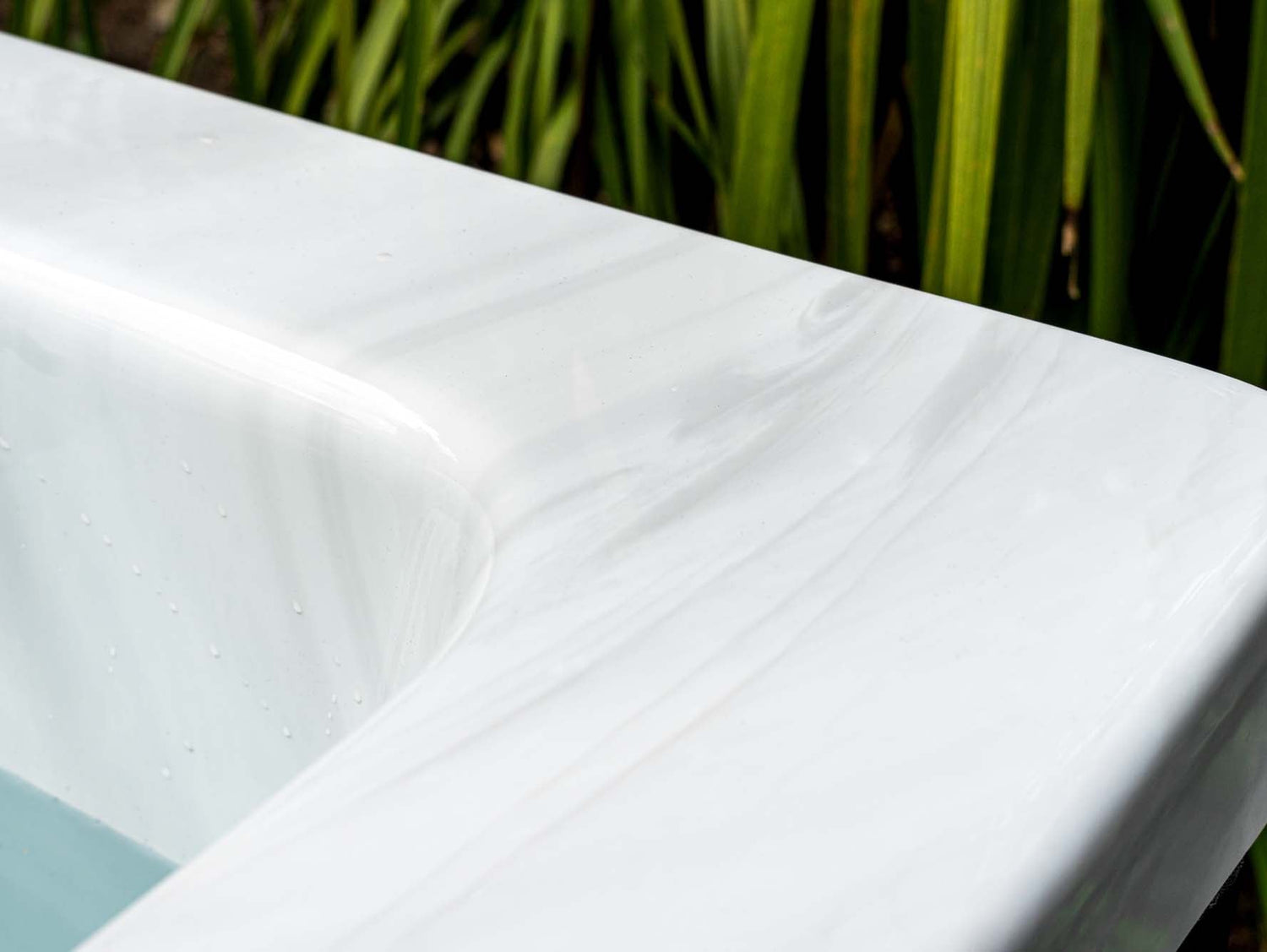 Modern white Breeze ice bath with current system shown against natural green foliage, highlighting sleek rim design - Passion Ice Baths Collection