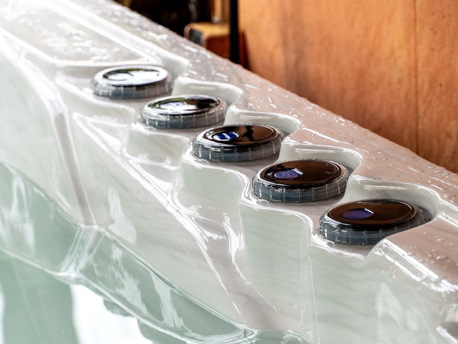 Elevate ice bath with five circular control panels on white acrylic edge, featuring LED-lit jets by Passion Ice Baths