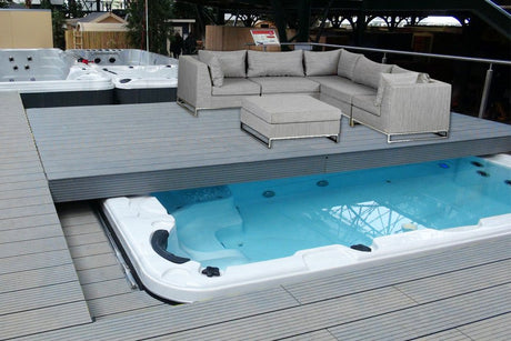 Fitness 1 Deep swim spa with grey deck seating area and modern sectional sofa, showcasing Current-Lift technology - Passion Spas Fitness Collection