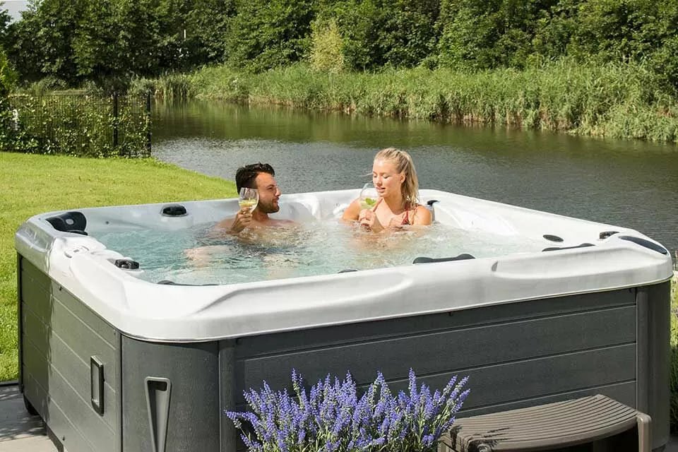 Luxurious Desire hot tub by pond with lavender garden, featuring grey cabinet and white shell, outdoor wellness - Passion Spas Signature Collection