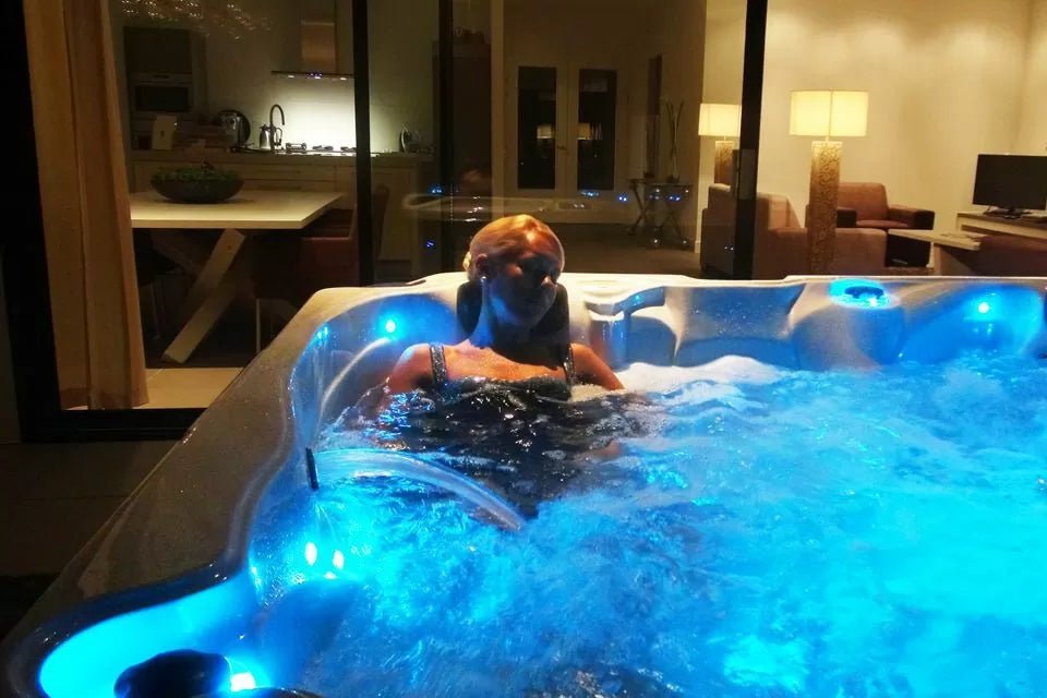Pleasure hot tub with blue LED lighting illuminating therapeutic waters in indoor showroom setting - Passion Spas Signature Collection