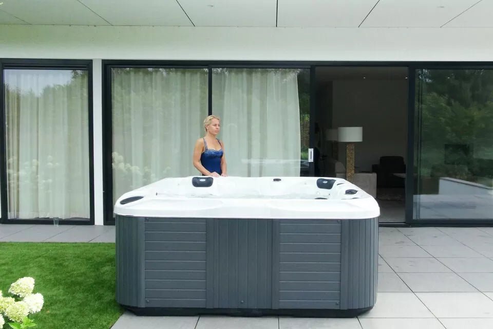 Admire luxury hot tub on modern patio with glass doors, showing spacious design and grey cabinet - Passion Spas Signature Collection Hot Tubs